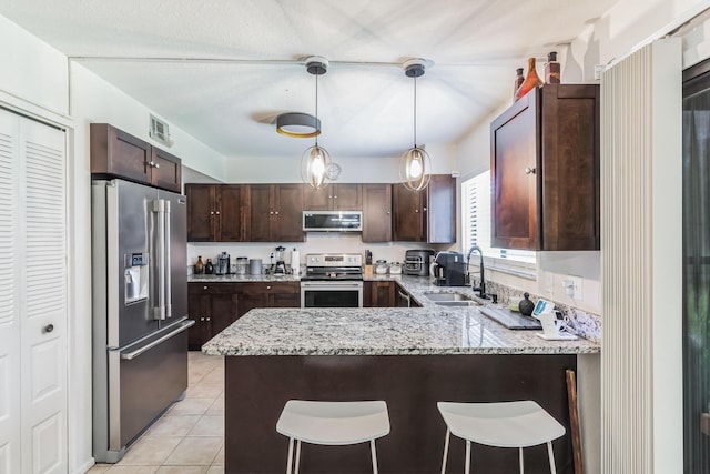 kitchen featuring stainless steel appliances, sink, a kitchen breakfast bar, and kitchen peninsula