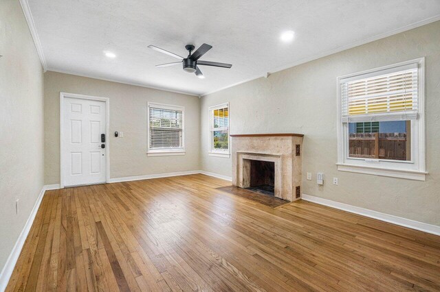 unfurnished living room with ceiling fan, light hardwood / wood-style flooring, a fireplace, and crown molding