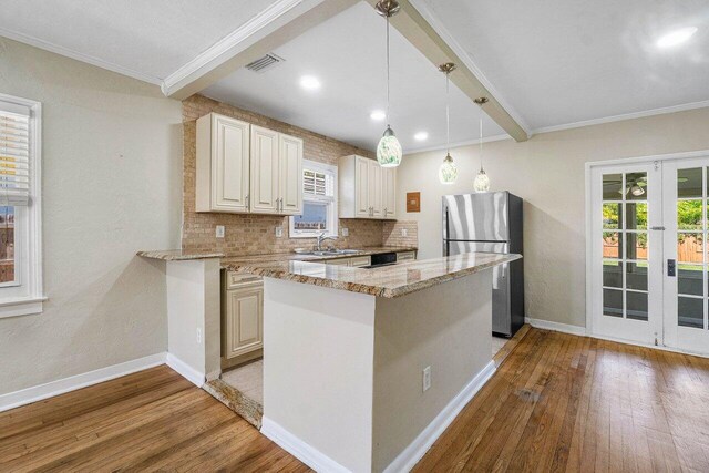 kitchen featuring beam ceiling, stainless steel fridge, light stone counters, and hardwood / wood-style floors