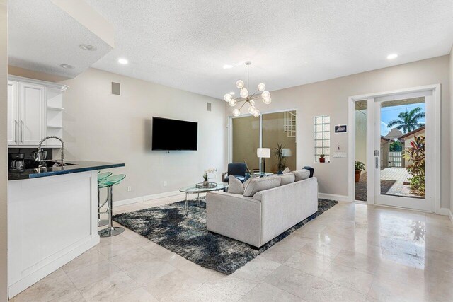 living room with a textured ceiling, an inviting chandelier, and sink