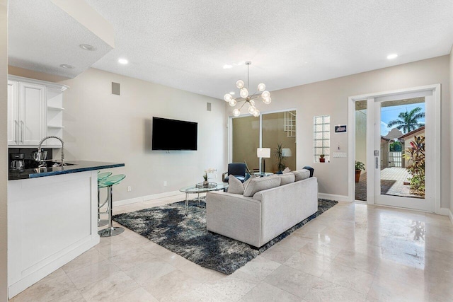 living room featuring a notable chandelier, sink, and a textured ceiling