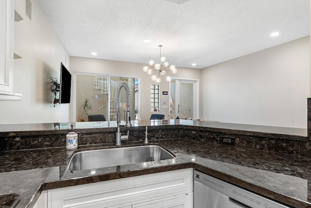 kitchen featuring pendant lighting, sink, a textured ceiling, a notable chandelier, and white cabinetry