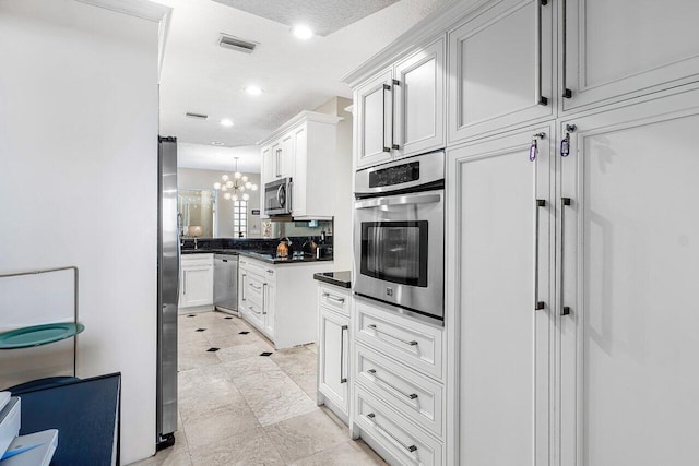 kitchen featuring pendant lighting, white cabinets, a textured ceiling, appliances with stainless steel finishes, and a chandelier