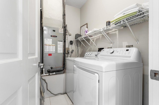 clothes washing area featuring washing machine and dryer, heating unit, light tile patterned floors, and a textured ceiling