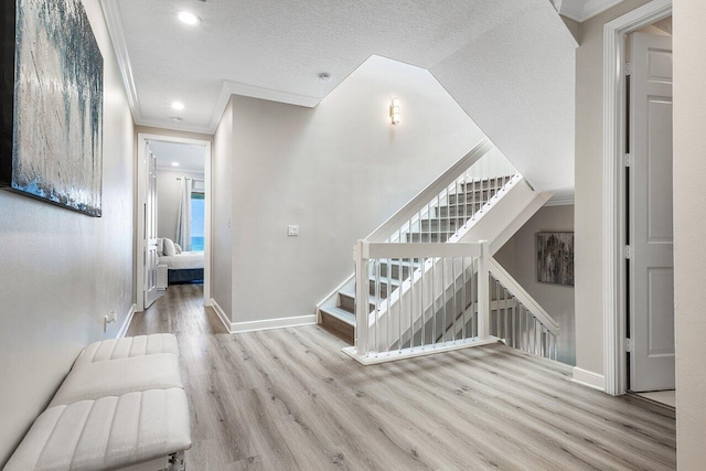 stairs with wood-type flooring, a textured ceiling, and ornamental molding