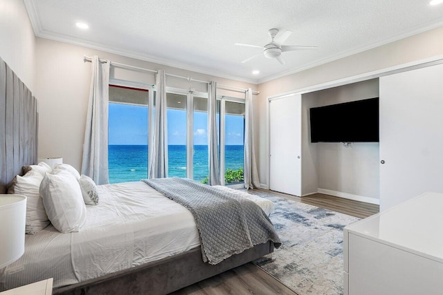 bedroom featuring ceiling fan, hardwood / wood-style floors, a textured ceiling, access to outside, and ornamental molding