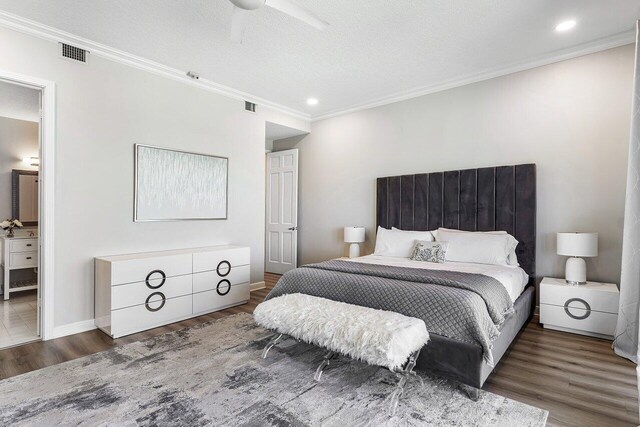 bedroom featuring ensuite bath, ceiling fan, ornamental molding, a textured ceiling, and dark hardwood / wood-style flooring