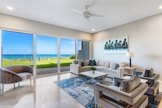 living room with a textured ceiling, a water view, and ceiling fan