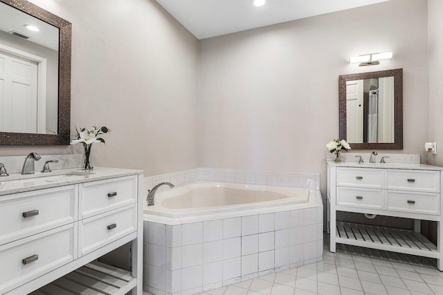 bathroom featuring vanity, tile patterned flooring, and tiled tub