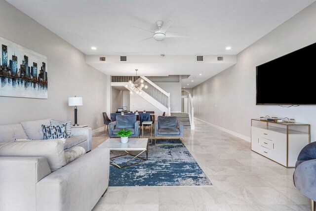 living room featuring a textured ceiling and ceiling fan with notable chandelier