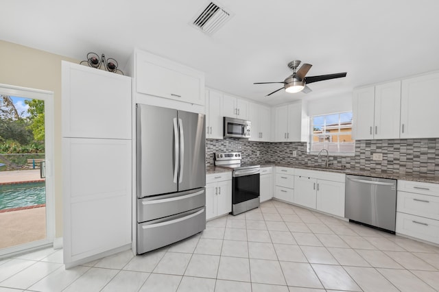 kitchen with ceiling fan, sink, stainless steel appliances, backsplash, and white cabinets