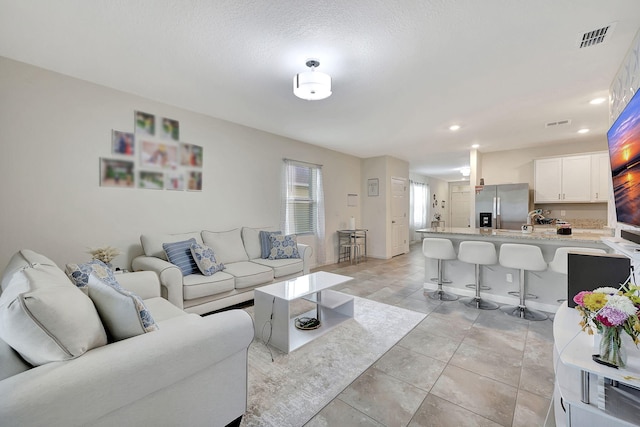 living room with a textured ceiling, sink, and light tile patterned floors