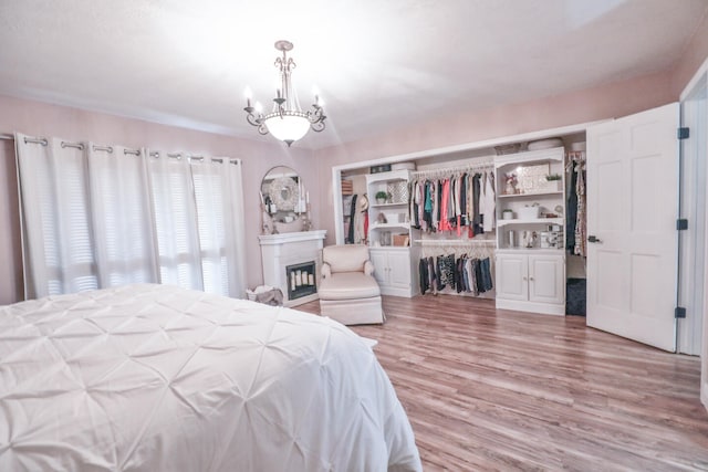 bedroom featuring light wood-type flooring, an inviting chandelier, and a closet