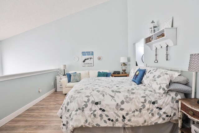 bedroom with vaulted ceiling and light hardwood / wood-style flooring