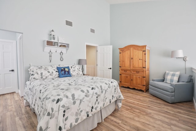 bedroom with a towering ceiling and light wood-type flooring