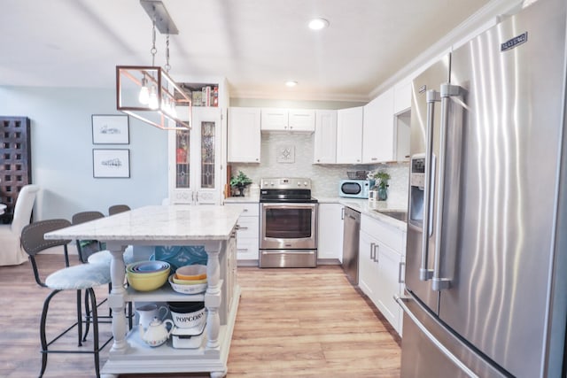 kitchen with a breakfast bar, light hardwood / wood-style flooring, decorative backsplash, stainless steel appliances, and white cabinets