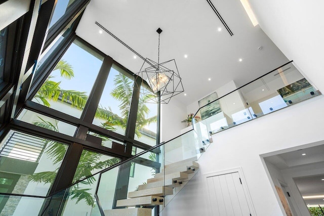 staircase with a high ceiling and a notable chandelier