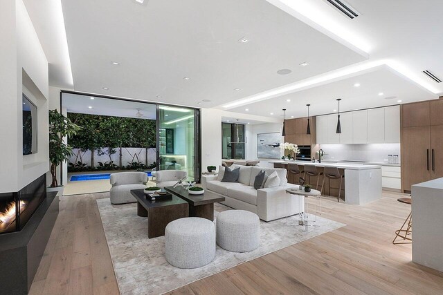 living room with sink, light hardwood / wood-style floors, and a multi sided fireplace