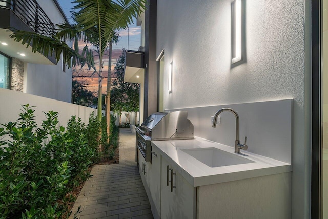 patio terrace at dusk featuring area for grilling and sink