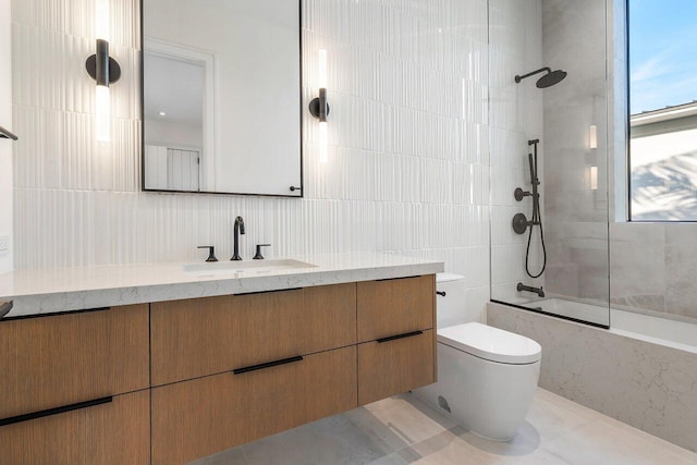 full bathroom with tiled shower / bath, tile walls, vanity, and toilet