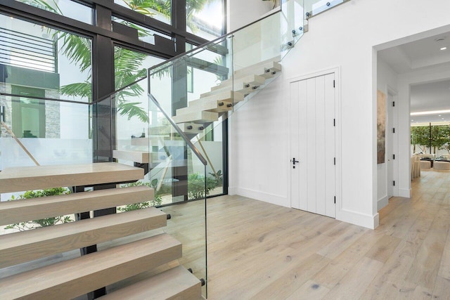 staircase featuring hardwood / wood-style floors, a high ceiling, and a healthy amount of sunlight