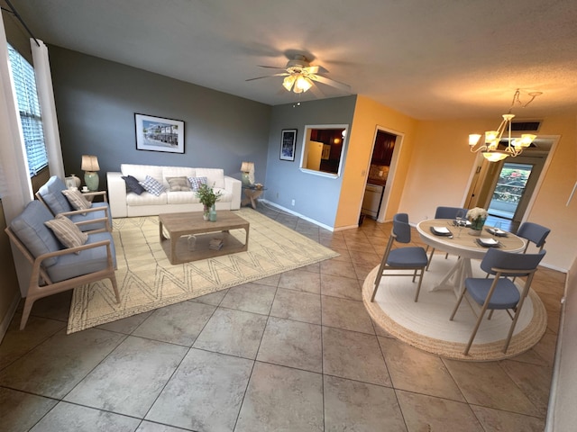 living area with ceiling fan with notable chandelier, light tile patterned floors, and baseboards