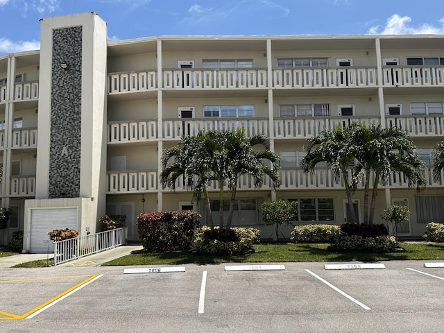 view of building exterior with uncovered parking and fence