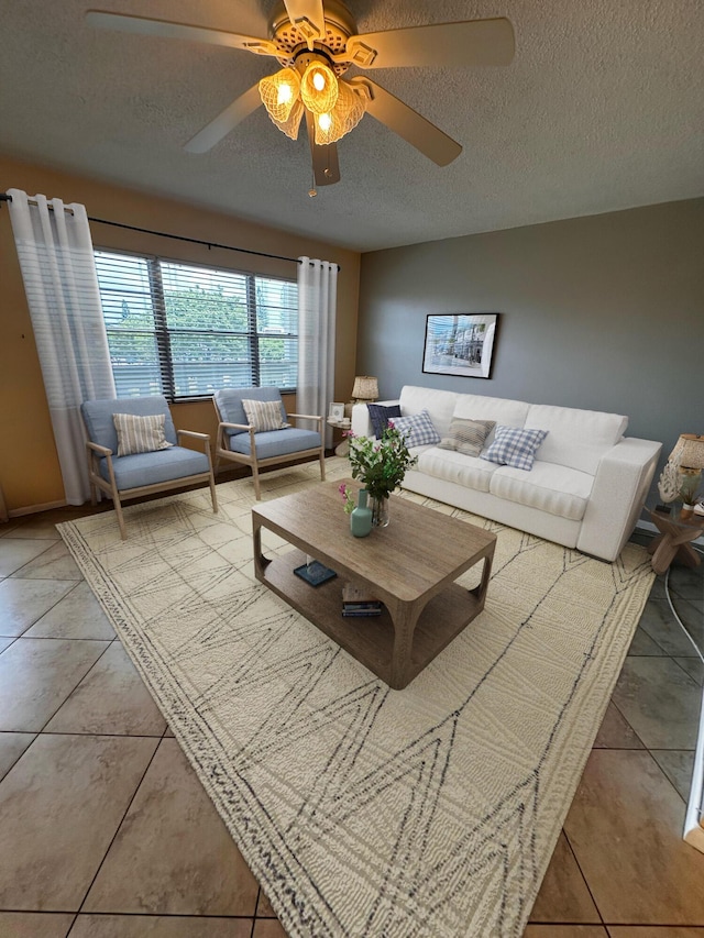 living area with ceiling fan, a textured ceiling, and light tile patterned flooring