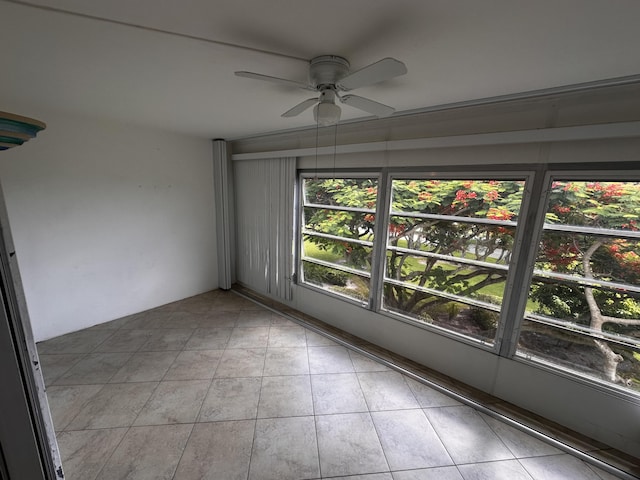 tiled empty room featuring ceiling fan and a healthy amount of sunlight