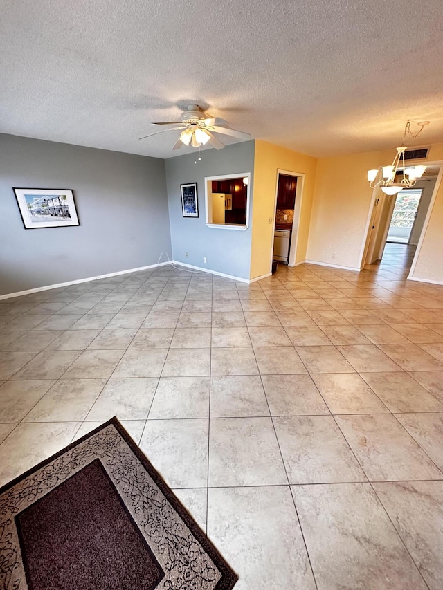 unfurnished living room with light tile patterned floors, baseboards, a textured ceiling, and ceiling fan with notable chandelier