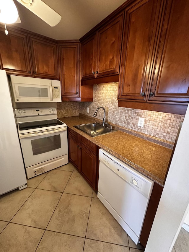 kitchen with light tile patterned flooring, white appliances, a sink, decorative backsplash, and dark countertops