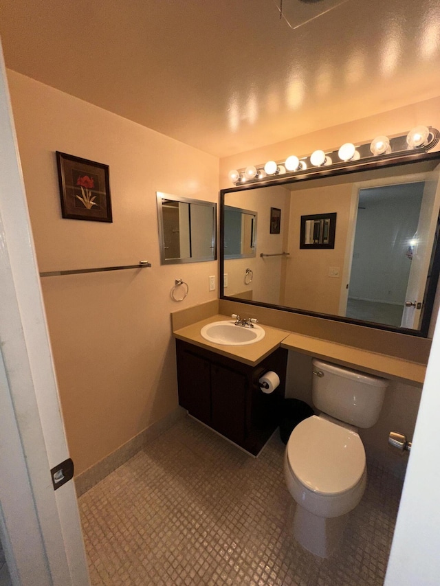 bathroom with toilet, tile patterned flooring, vanity, and baseboards