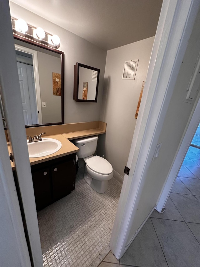 half bathroom featuring visible vents, baseboards, toilet, tile patterned flooring, and vanity