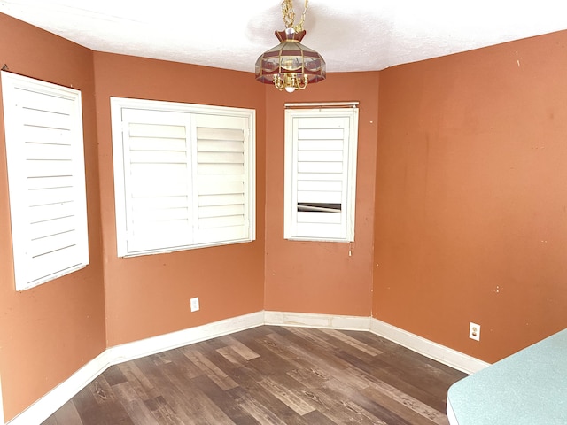 unfurnished room featuring dark hardwood / wood-style floors, a textured ceiling, and a chandelier