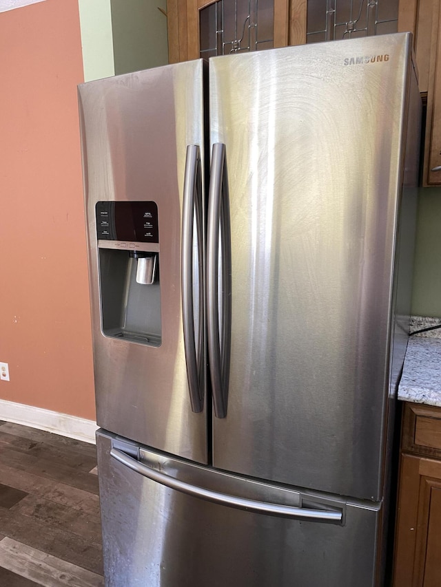 room details featuring stainless steel fridge with ice dispenser, dark wood-type flooring, and light stone countertops