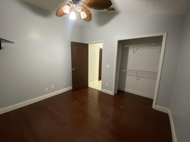 unfurnished bedroom with ceiling fan, a towering ceiling, dark wood-type flooring, and a closet