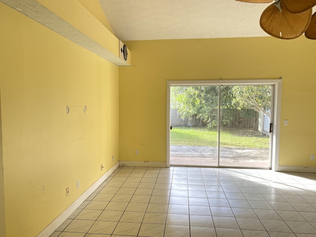 tiled empty room with ceiling fan and vaulted ceiling