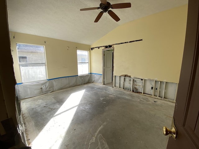 spare room featuring a textured ceiling, ceiling fan, concrete flooring, and lofted ceiling