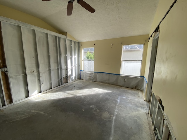 unfurnished room with a textured ceiling, a barn door, ceiling fan, and lofted ceiling