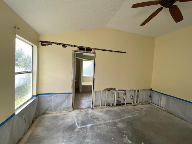 empty room with a textured ceiling, ceiling fan, and lofted ceiling