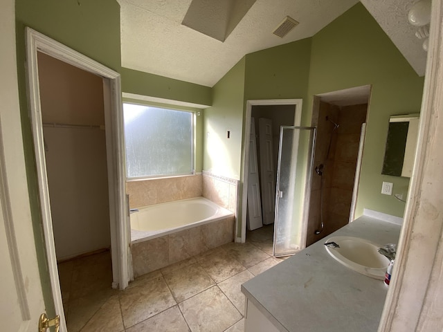 bathroom with vanity, a textured ceiling, vaulted ceiling, tile patterned floors, and independent shower and bath