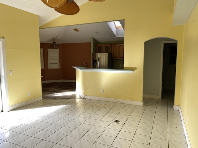 interior space featuring ceiling fan, lofted ceiling with skylight, sink, and light tile patterned floors