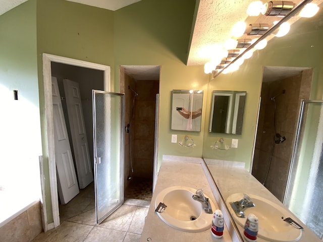 bathroom with tile patterned floors, vanity, a shower with shower door, and a textured ceiling