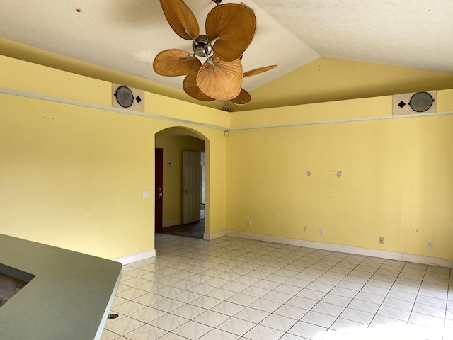 empty room featuring lofted ceiling, light tile patterned floors, and ceiling fan