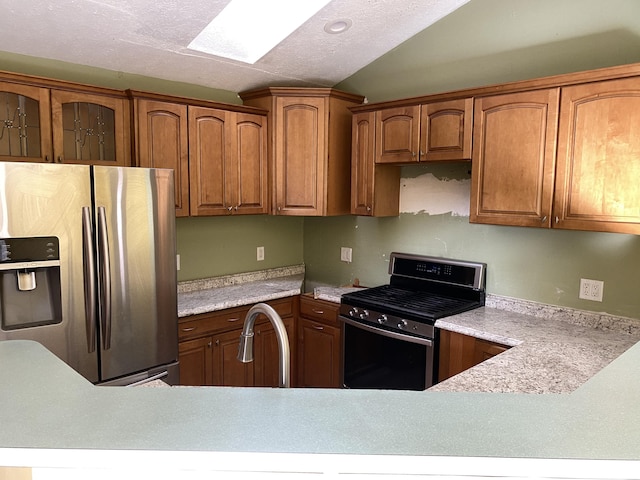 kitchen featuring appliances with stainless steel finishes, sink, vaulted ceiling, and a textured ceiling