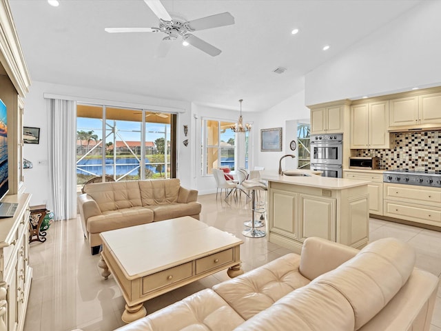 tiled living room with sink, high vaulted ceiling, ceiling fan with notable chandelier, and a water view