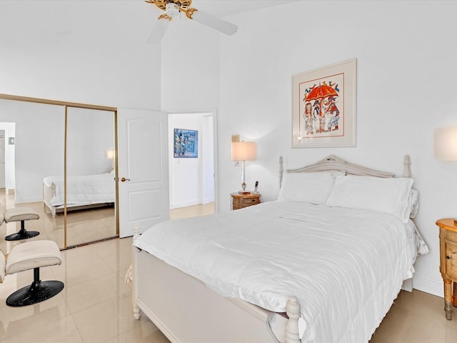 bedroom with ceiling fan, a closet, light tile patterned flooring, and a towering ceiling