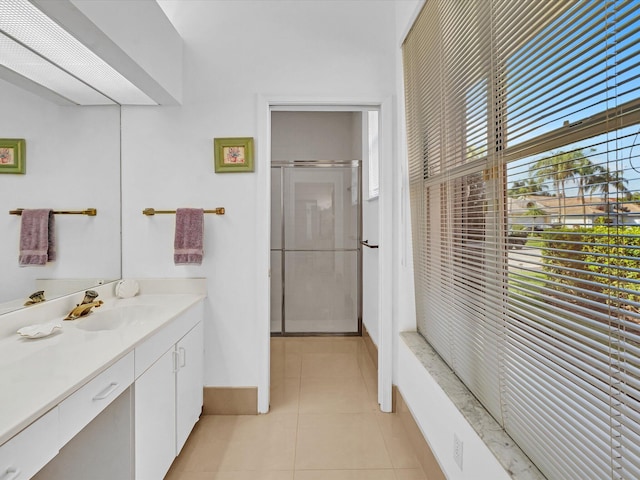 bathroom with a shower with shower door, vanity, and tile patterned floors