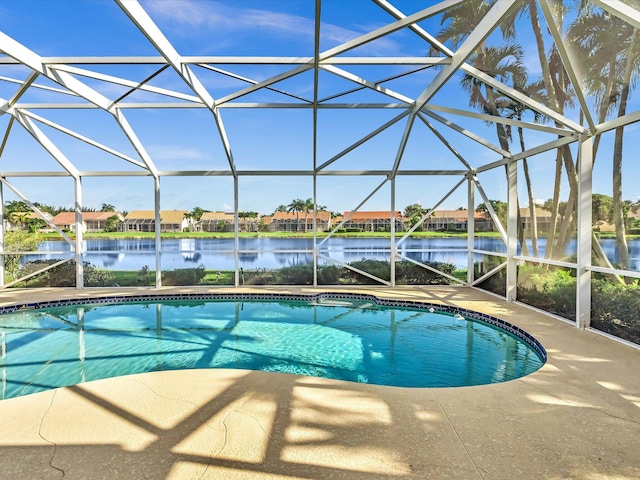 view of pool featuring glass enclosure, a water view, and a patio