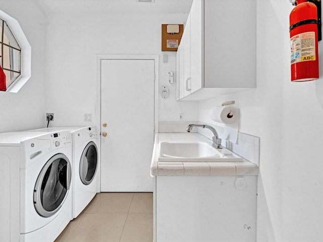 laundry area featuring separate washer and dryer, sink, light tile patterned floors, and cabinets